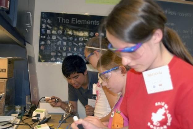 MIT student Victor Morales, far left, teaches students how to solder electronic connections. (Courtesy MIT Edgerton Center)