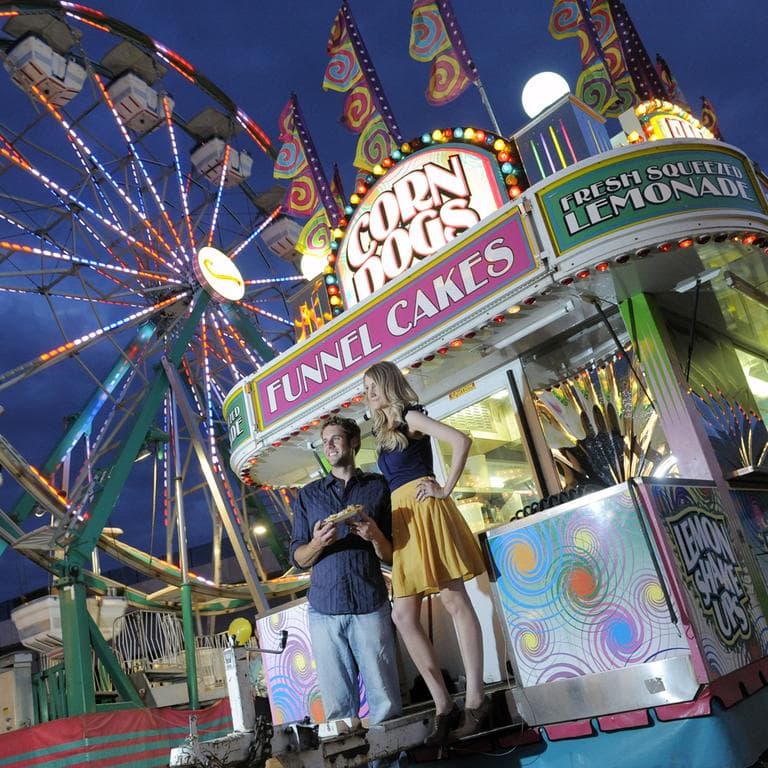 Luke Gunn, left, and Jacqueline Allee, right, both of Pueblo, have their picture taken on the midway for an engagement photo session at the first Denver County Fair in Denver. (AP)