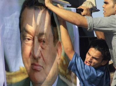 An Egyptian pro-Mubarak protester erects a poster of the ousted president on Wednesday outside the police academy in Cairo. (AP)