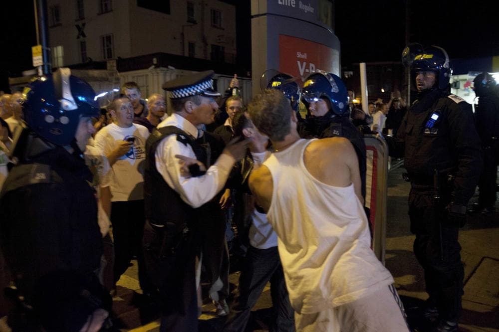 Police officers scuffle with men as members of the community march to reclaim their streets on Tuesday in Enfield, North London. (AP)