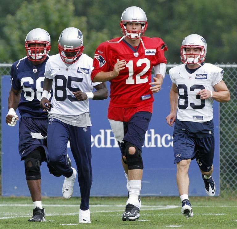Patriots quarterback Tom Brady (12) runs a drill with defensive end Aaron Carter, left, wide receiver Chad Ochocinco (85) and wide receiver Wes Welker (83) during training camp in Foxborough, Tuesday. (AP)