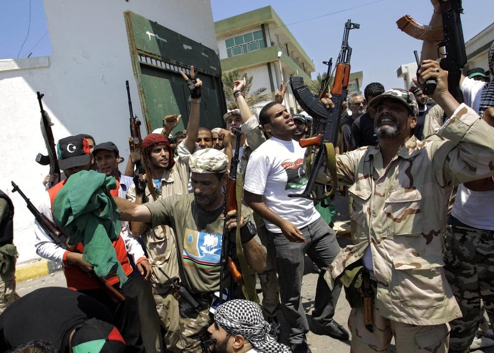 Libyan rebel fighters gesture at the former female military base in Tripoli, Libya. (AP)