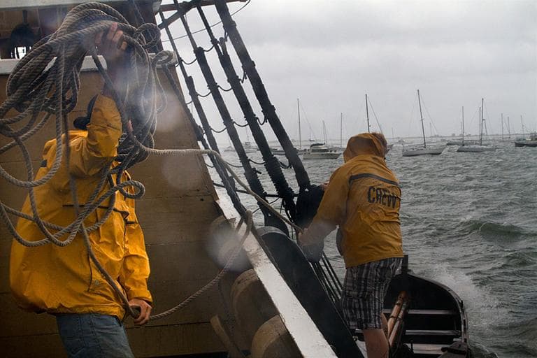 Crewmembers of the Mayflower II in Plymouth struggle to wrangle a loose utility boat. (Jesse Costa/WBUR)