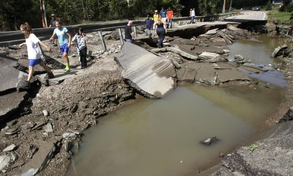 People walk along a section of Route 12 washed out by Hurricane Irene on Monday, in Berlin, VT. (AP)