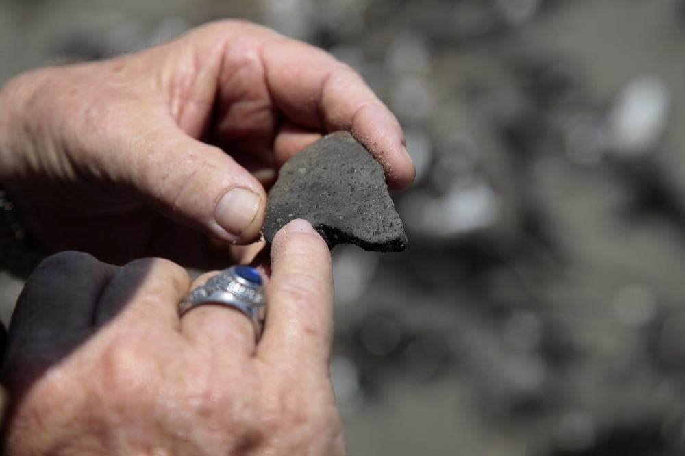 Forrest Travirca III, looks at an ancient pottery shard he found as he walks along Port Fourchon Beach searching for artifacts from Pre-historic American-Indian settlements in Caminada Headland, La. (AP)