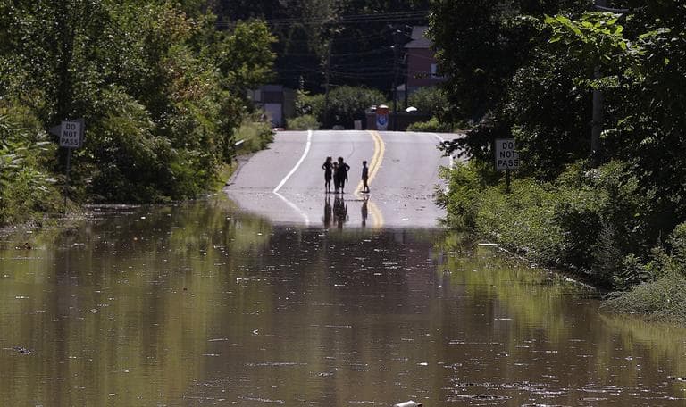 Children stand on the far side of a flooded portion of Massachusetts Rt. 5 which was closed to traffic in Northhampton, Mass., Monday. (AP)