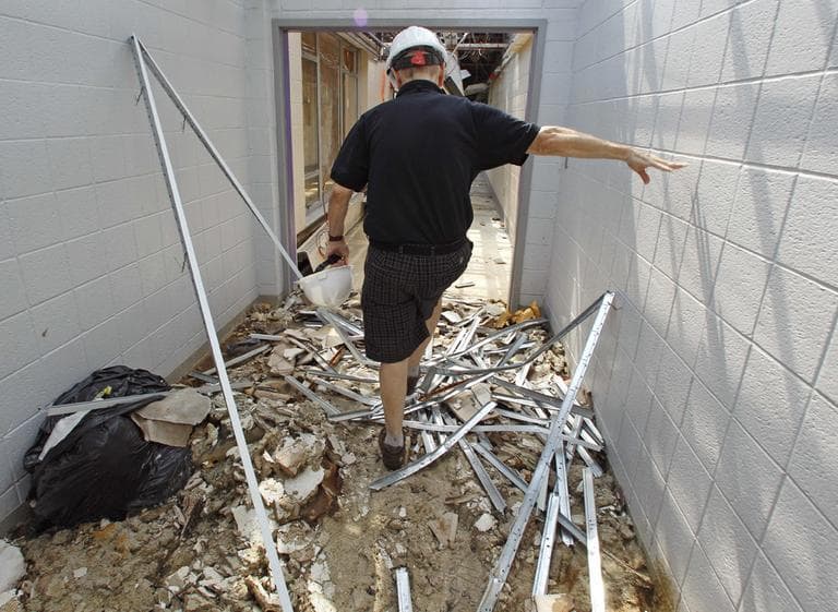 In this Aug. 24 photo, Bill McBride, the associate principal of Cathedral High School, climbs over debris while walking down a school corridor. (AP)