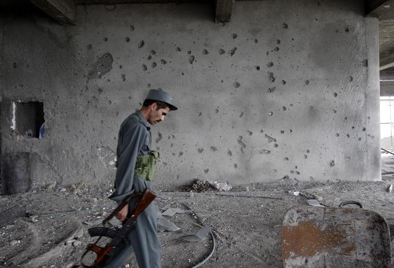 An Afghan police officer passes by a shattered wall of the building which was occupied by Taliban militants during the insurgent attack in Kabul on Wednesday. (AP) 