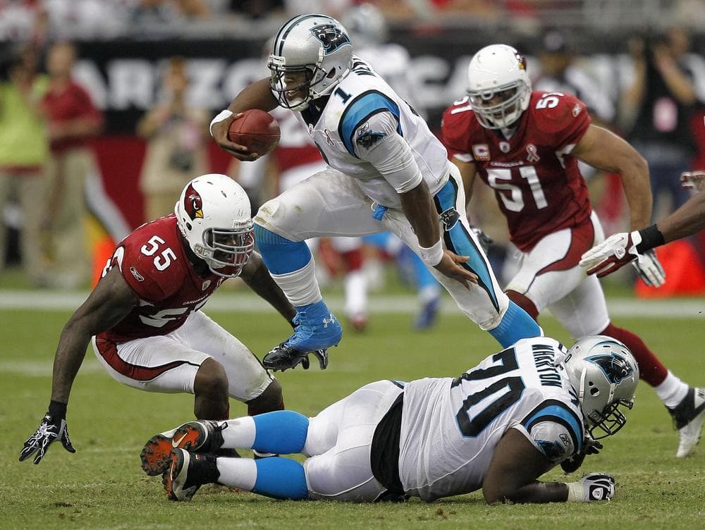 Carolina Panthers quarterback Cam Newton leaps over teammate Travelle Wharton as Arizona Cardinals' Joey Porter and Paris Lenon pursue him during last Sunday's game. Newton threw 24/37 for 422 yards in his professional debut.
