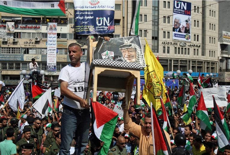 Palestinians hold up a chair with a picture of late Palestinian leader Yasser Arafat and wave flags during a rally in support of the Palestinian bid for statehood recognition in the United Nations, in the West Bank city of Nablus, Wednesday, Sept. 21, 2011. (AP)