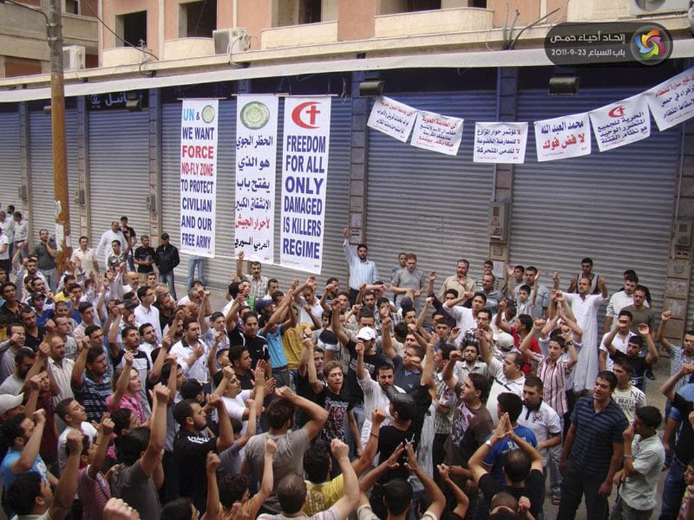 In this citizen journalism image made on a mobile phone and provide by Homs Quarters Union, anti-Syrian President Bashar Assad protesters shout slogans during a demonstration against the Syrian regime, in Homs province, Syria, on Friday.The Arabic banner in the center background read:&quot;A no-fly zone opens the door for the free soldiers of the Syrian army to defect.&quot; (AP /Homs Quarters Union)