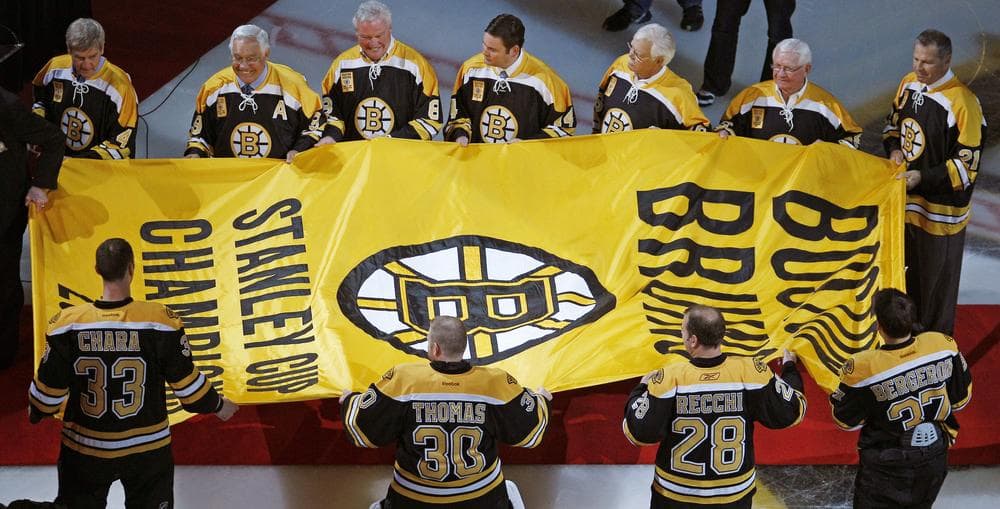 Members of the Boston Bruins' 1972 Stanley Cup championship team and the current Bruins team carry the 2011 Stanley Cup banner across the ice of the Boston Garden prior to the Bruins game against the Philadelphia Flyers on Thursday. (AP)
