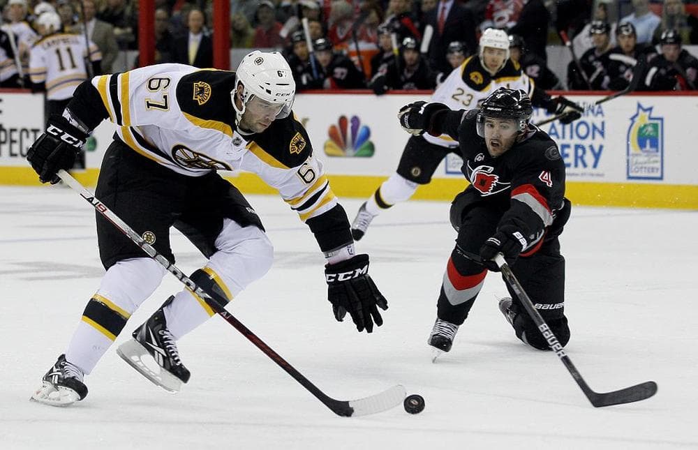 Boston Bruins' Benoit Pouliot controls the puck as Carolina Hurricanes' Jamie McBain defends. (AP)