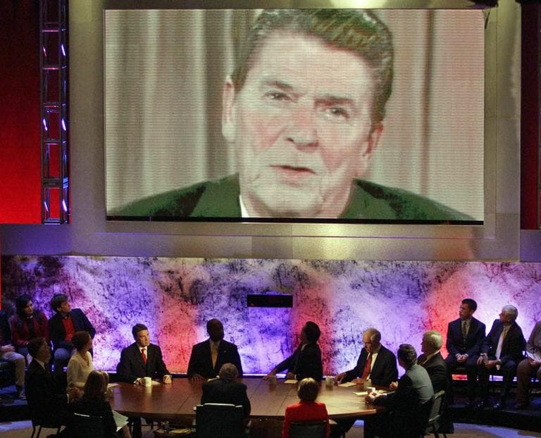 The eight Republican presidential candidates sitting at the table listen as a video of former President Ronald Reagan is played during a Republican presidential debate at Dartmouth College in Hanover, N.H., Tuesday night, Oct. 11, 2011. (AP)