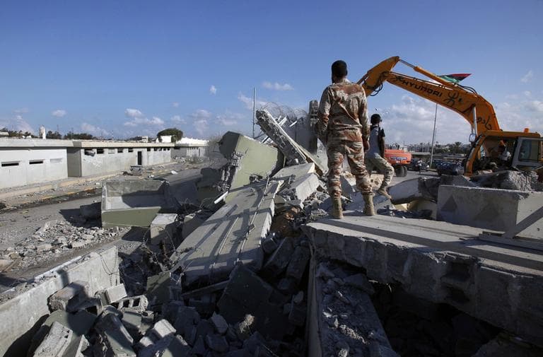 Revolutionary fighters use heavy machinery to tear down a guard tower at the Bab al-Aziziya compound in Tripoli, Libya on Sunday. (AP)