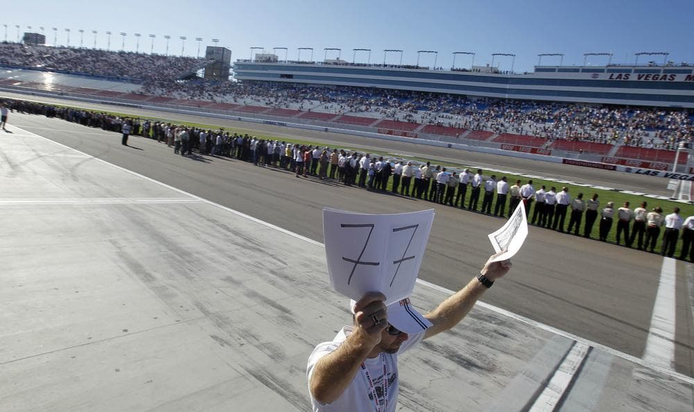 Fans, drivers and teams stand in honor of Dan Wheldon who died following a crash in the IndyCar Series' Las Vegas Indy 300 auto on Sunday. Wheldon was driving car No. 77. (AP)