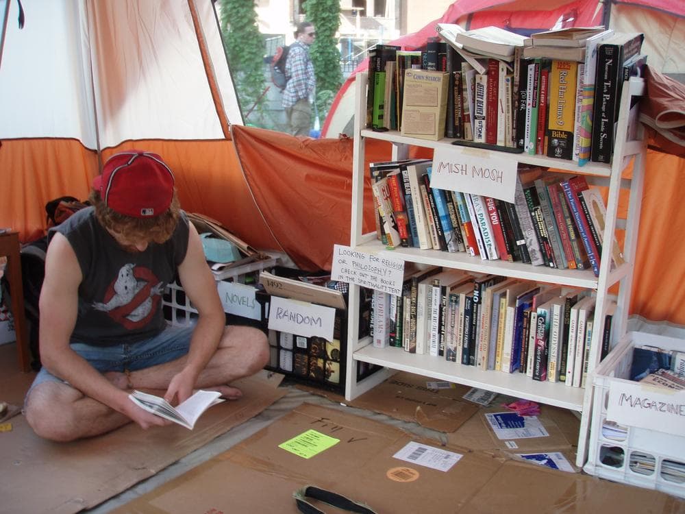 Occupy Boston protester Sean Eason reads Noam Chomsky in the camp's library tent. (Curt Nickisch/WBUR)
