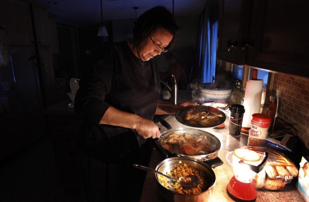 Tracy Ward of Wilbraham prepares dinner by lantern light for her family on Monday. (AP)