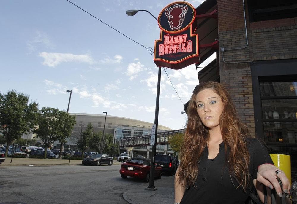 Caitlin Cassidy, a manager at the Harry Buffalo, sits at a table with the Quicken Loans Arena in the background, in Cleveland. (AP)