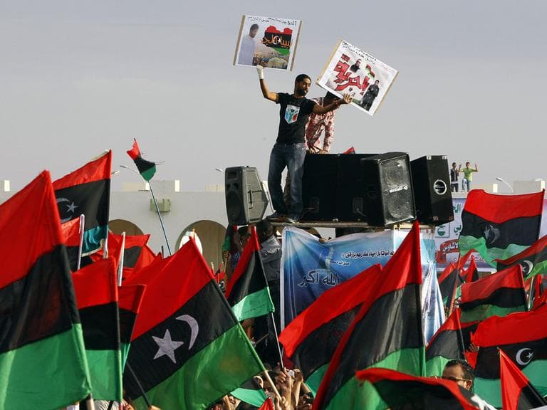 A Libyan wounded youth holds up portraits of martyrs during the celebration at Saha Kish Square in Benghazi, Libya, Sunday Oct. 23, 2011 as Libya's transitional government declare liberation of Libya after months of bloodshed that culminated in the death of longtime leader Moammar Gadhafi. (AP)