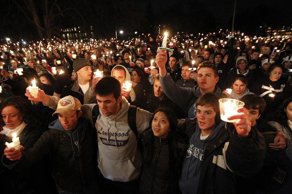 People gather in front of the Old Main building for a candlelight vigil in support of child abuse victims on the Penn State campus on Friday, in State College, PA.
