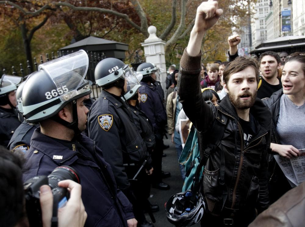 Police in riot gear watch as Occupy Wall Street protesters march past City Hall in New York, Tuesday. (AP)