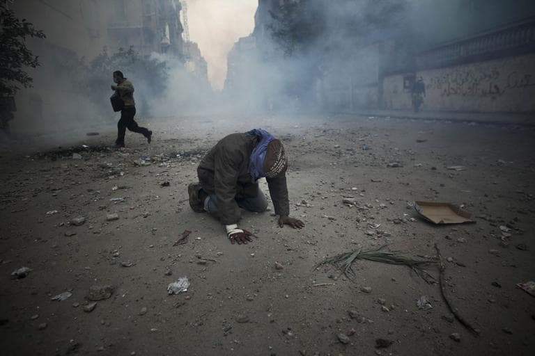A protester overcome with tear gas inhalation kneels in the middle of the street during clashes with the Egyptian riot police, not seen, near the interior ministry in downtown Cairo, Egypt, Sunday, Nov. 20. (AP)