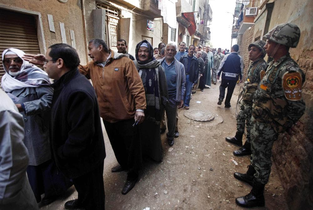 Egyptian army soldiers stand guard as voters line up outside a polling center in Assuit, south of Cairo, Egypt. (AP)