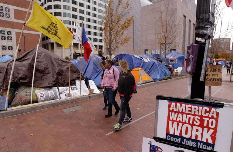 Pedestrians walk along Atlantic Avenue in front of the Occupy Boston encampment Nov. 16. (AP)