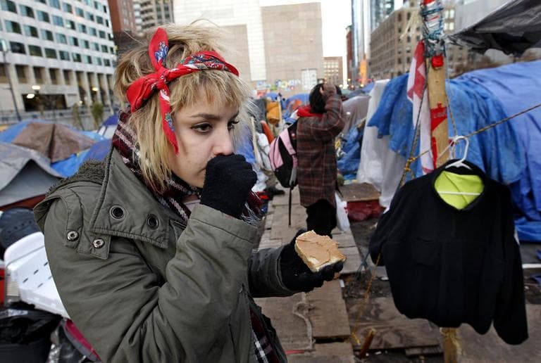 A protester from Portland, Maine, warms her hand with her breath while eating a sandwich at the Occupy Boston encampment, in Boston on Wednesday. (AP)