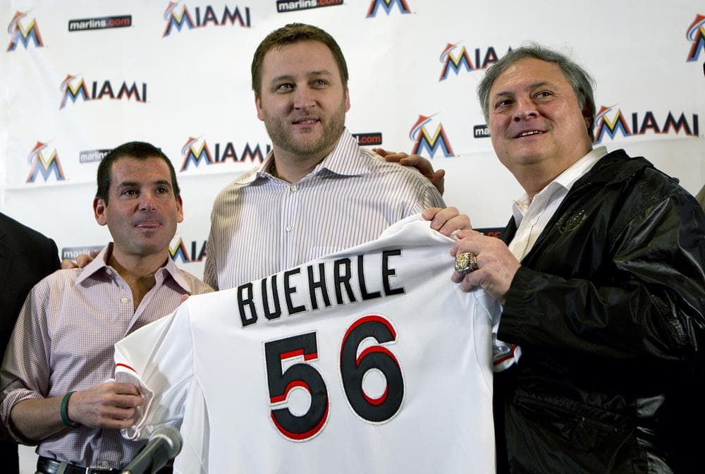Miami Marlins president David Sampson and owner Jeffrey Loria pose for photos with recent addition, pitcher Mark Buehrle, on Friday. The left-hander Buehrle signed a $58 million, four-year contract with the club. (AP)