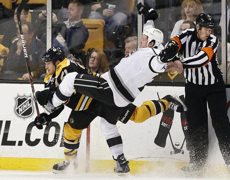 Los Angeles Kings center Colin Fraser goes flying after colliding with Boston Bruins defenseman Andrew Ference as referee Dave Jackson protects himself in the second period of an NHL hockey game in Boston. The Bruins won 3-0. (AP)