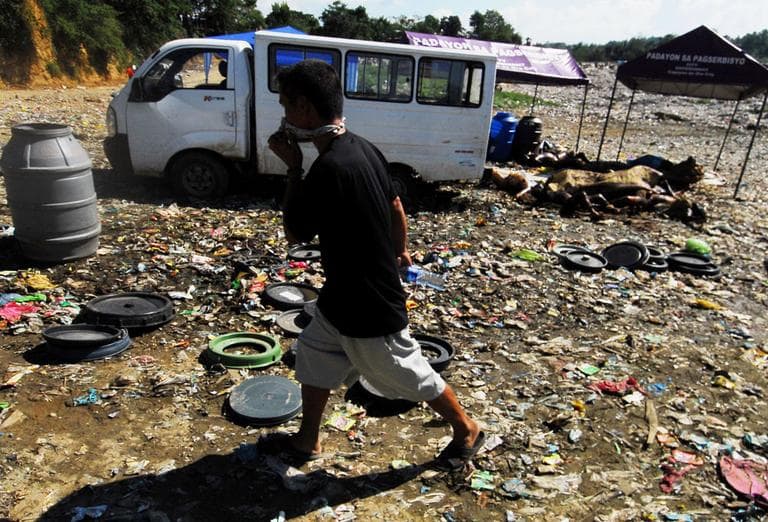 A resident covers his nose as he passes by decomposed bodies in a city garbage dump in Cagayan De Oro city, southern Philippines, Monday, Dec. 19. (AP)