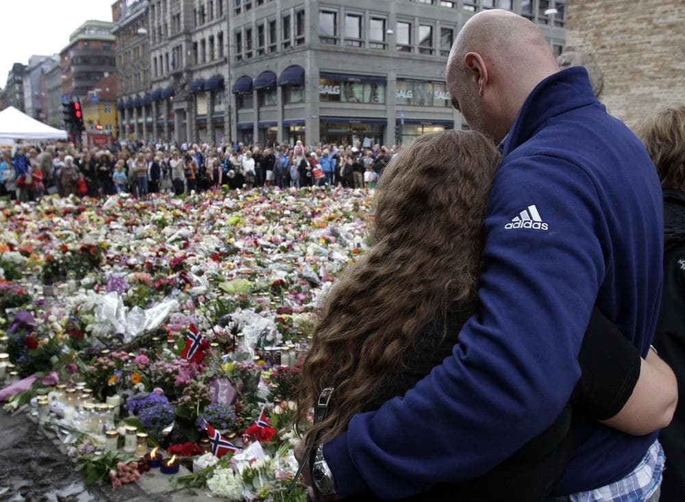 People embrace and mourn at the massive flower field laid in memory of victims of Friday's twin attacks in front of the Oslo Cathedral in Oslo, Norway, in July. (AP)