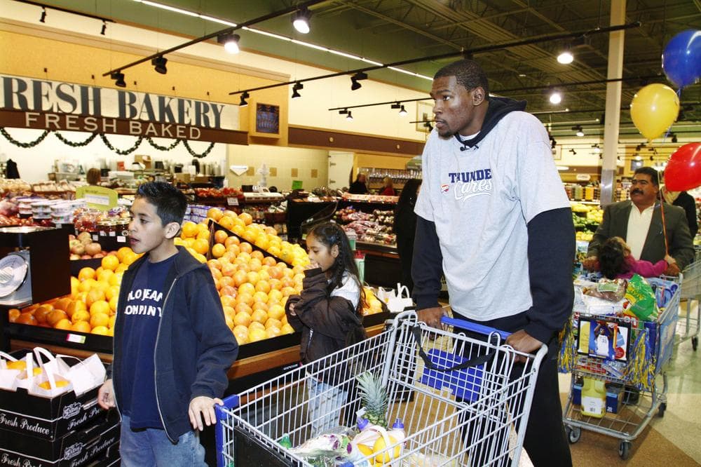 In the spirit of the season: Oklahoma City Thunder star Kevin Durant with a family in need that received a grocery store shopping spree this month. (AP)