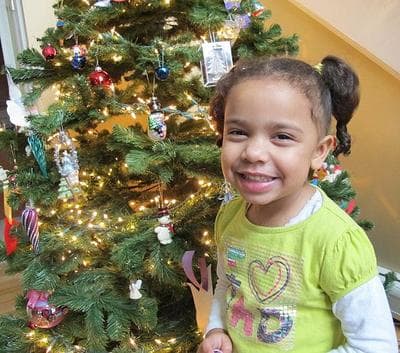 Gianna Montero smiles by the Christmas tree she helped put up before her father came home from Iraq. (Monica Brady-Myerov/WBUR)