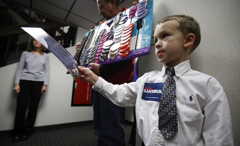 Four-year-old Austin Hall passes out campaign brochures for Republican presidential candidate Rick Santorum in Iowa on Sunday. A new Des Moines Register poll shows Santorum is gaining on front-runners Mitt Romney and Ron Paul. (AP)