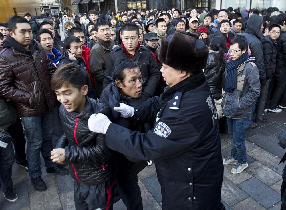 A policeman drags away people who refused to leave the Apple Store in Beijing Friday. (AP)