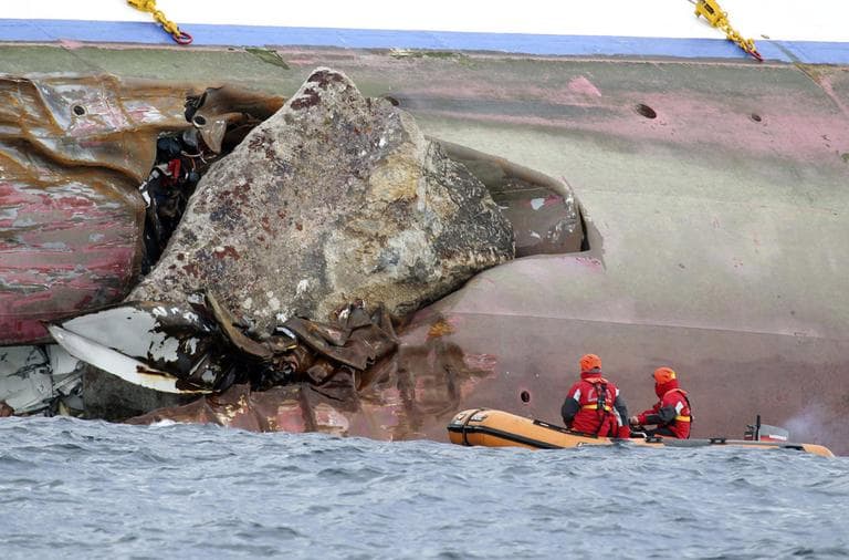 Firefighters on a dinghy look at a rock emerging from the side of the luxury cruise ship Costa Concordia, the day after it ran aground off the Tuscan island of Giglio, Italy, Sunday, Jan. 15. (AP)