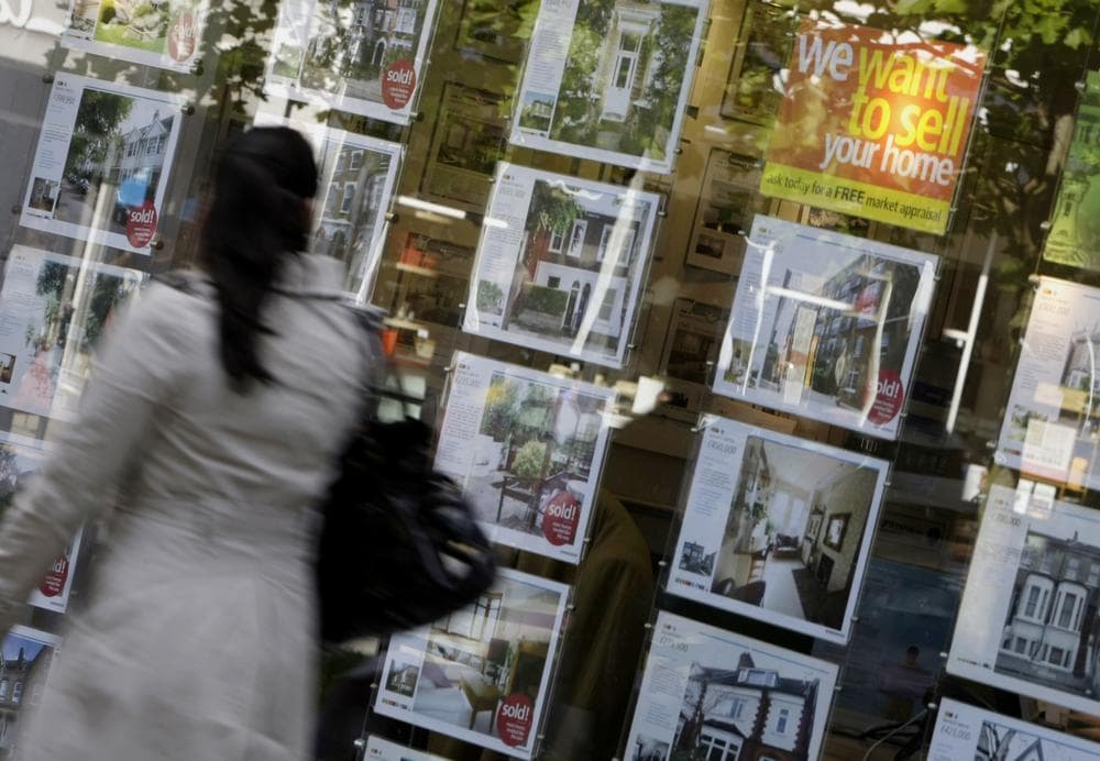 A woman walks past a real estate agent&#039;s window in west London. (AP)