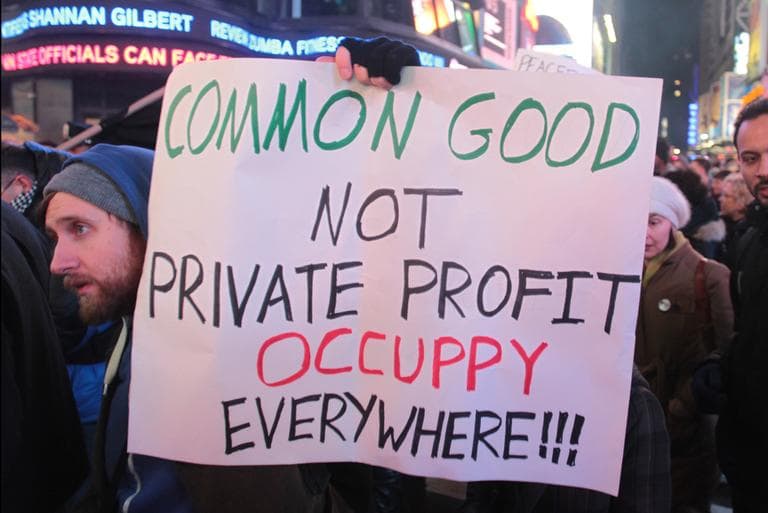 An Occupy Wall Street protester holds a sign as he marches in Times Square in New York, Saturday, Dec. 17, 2011. Earlier in the day dozens of Occupy Wall Street protesters were arrested as they attempted to enter an Episcopal church-owned lot in Manhattan's Tribeca neighborhood. (AP)