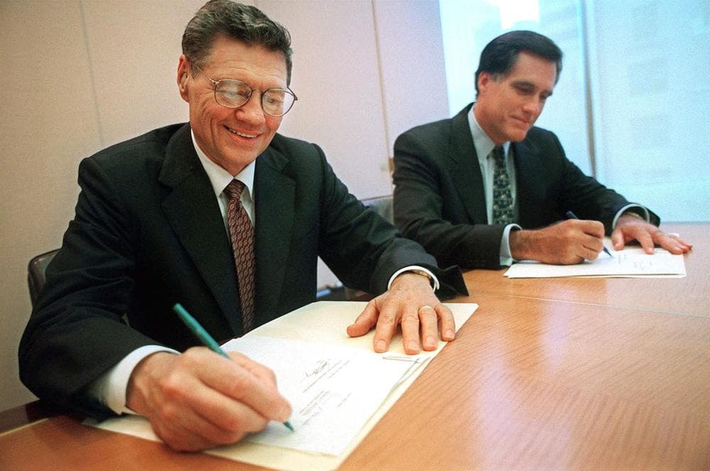 Thomas S. Monaghan, founder of Domino's Pizza, Inc., left, and Mitt Romney, then-managing director of Bain Capital, Inc., sign an agreement for Monaghan to sell a "significant portion" of his stake in the company to Bain Capital, in 1998. (AP)