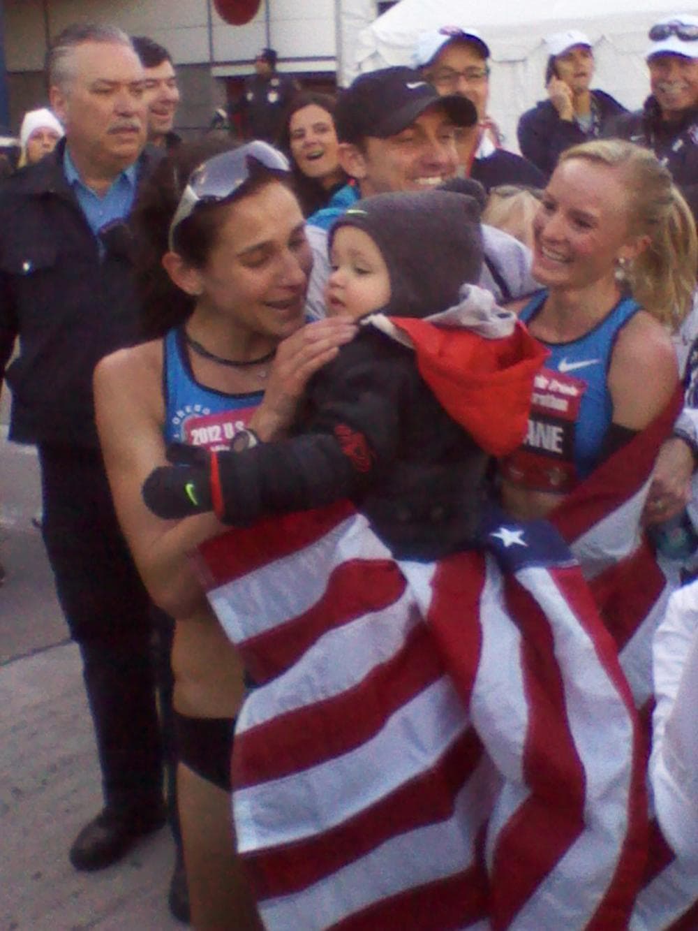 Kara Goucher, holding son Colt, and the women’s winner, Shalane Flanagan. (Alex Ashlock/WBUR)