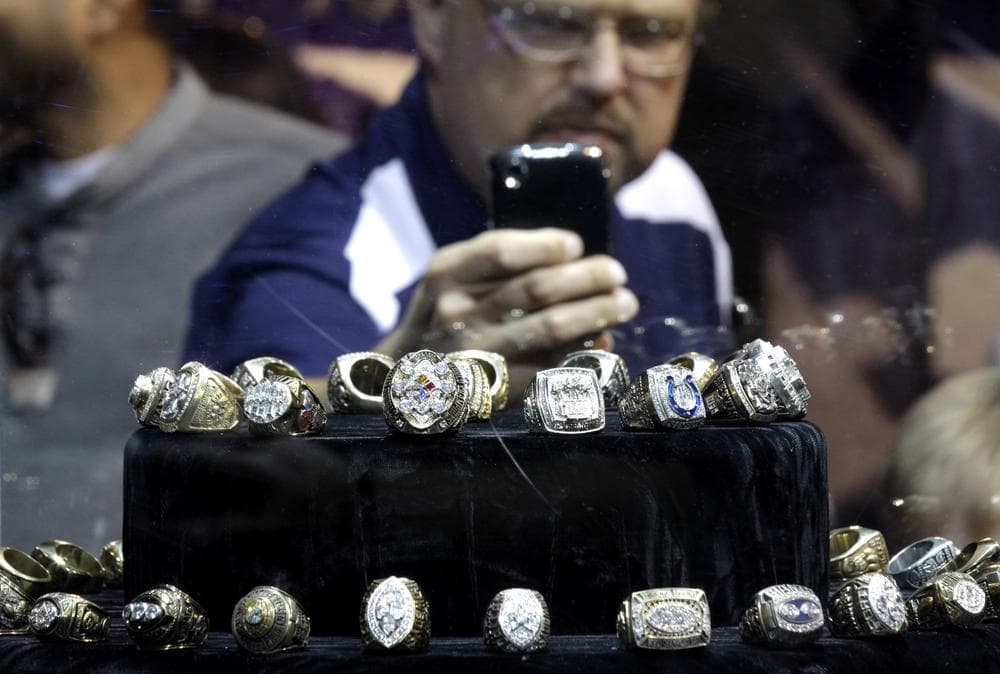 A fan photographs championship rings on display before last year's Super Bowl.  This year, one Hall of Famer will spend Super Bowl week talking about a different type of ring.  (AP)