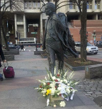 Flowers lay at the foot of Kevin White's statue near Faneuil Hall in Boston. (Lynn Jolicoeur/WBUR)