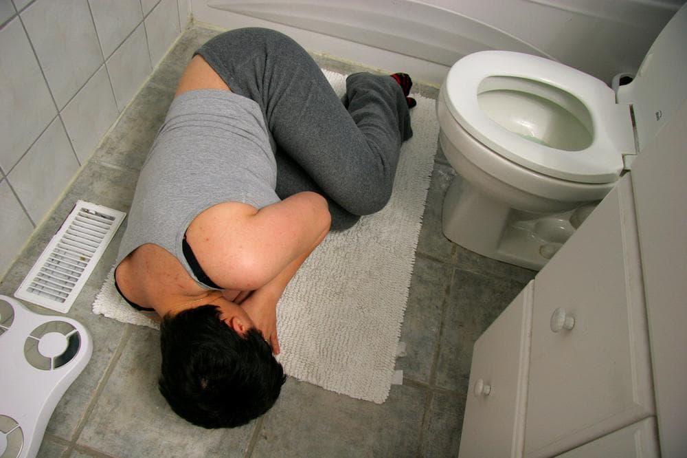 woman in the fetal position on the bathroom floor