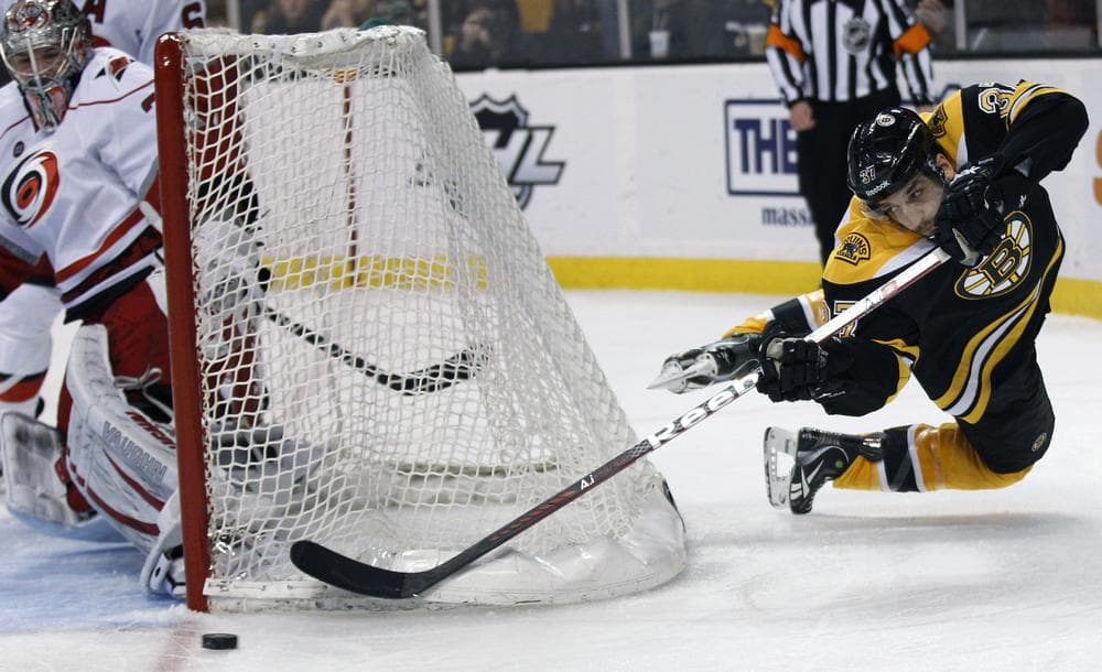 Bruins center Patrice Bergeron flies around the back of the net near Hurricanes goalie Cam Ward during the second period of a hockey game in Boston on Thursday. (AP)
