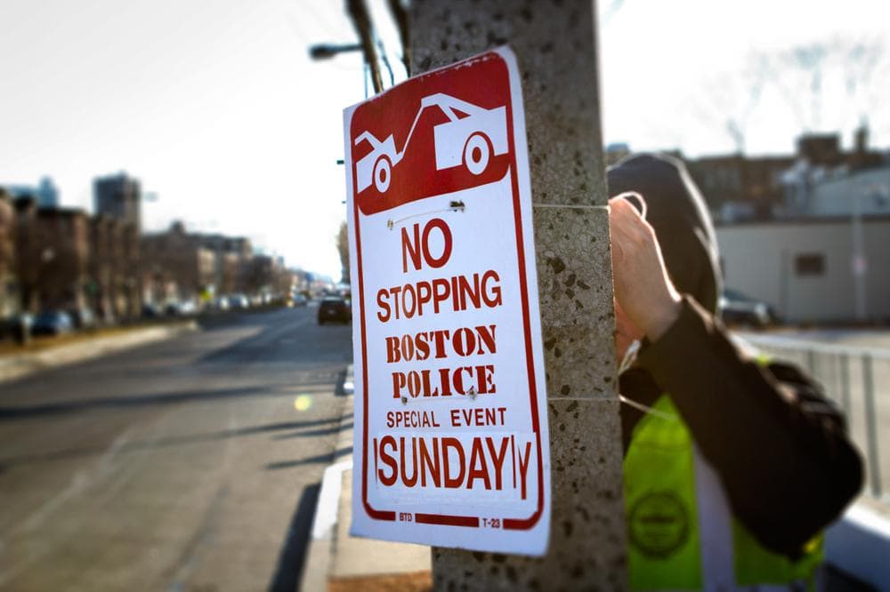 A Boston city worker hangs &quot;No Stopping&quot; signs Friday morning on Brighton Avenue in Allston in preparation for Super Bowl XLVI. (Jesse Costa/WBUR)