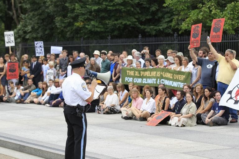 A U.S. Park Police officers speaks to demonstrators in front of the White House in Washington, Friday, Sept. 2, 2011, during a protest against the Keystone oil pipeline in the US, and the Tar Sands Development in Alberta Canada . (AP)