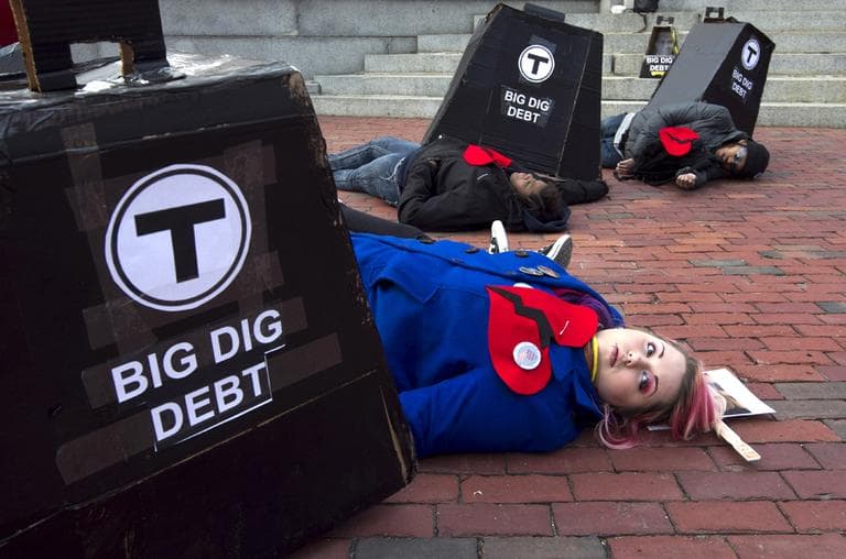 Allison Case, of Boston, front, pretends to be crushed under Big Dig debt, along with other protesters during a demonstration in front of the State House on Feb. 14. (AP)